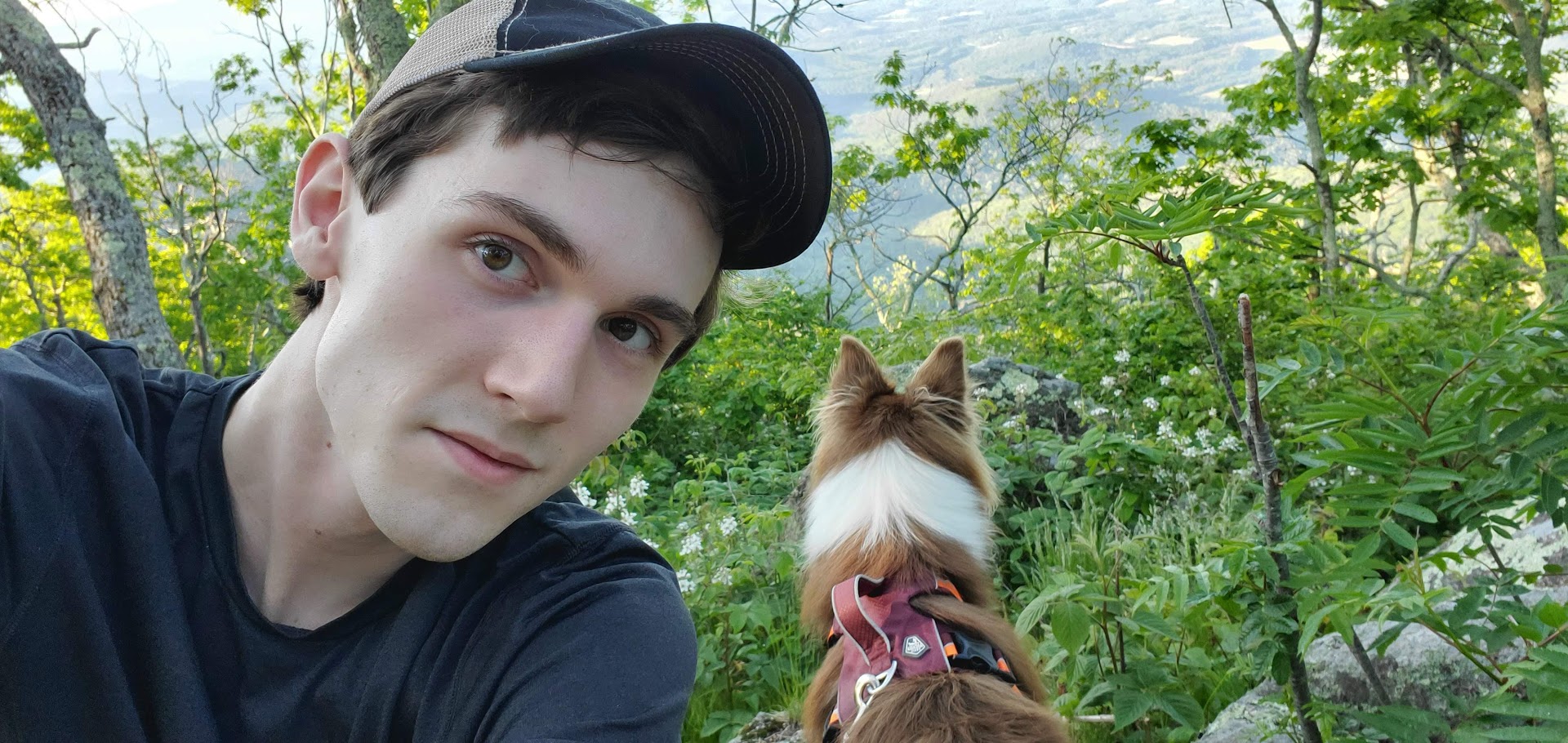 A selfie of Kelton Sullivan on a hike with his dog in the mountains of Virginia